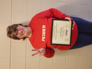 A woman in a Pender sweatshirt holds an award.